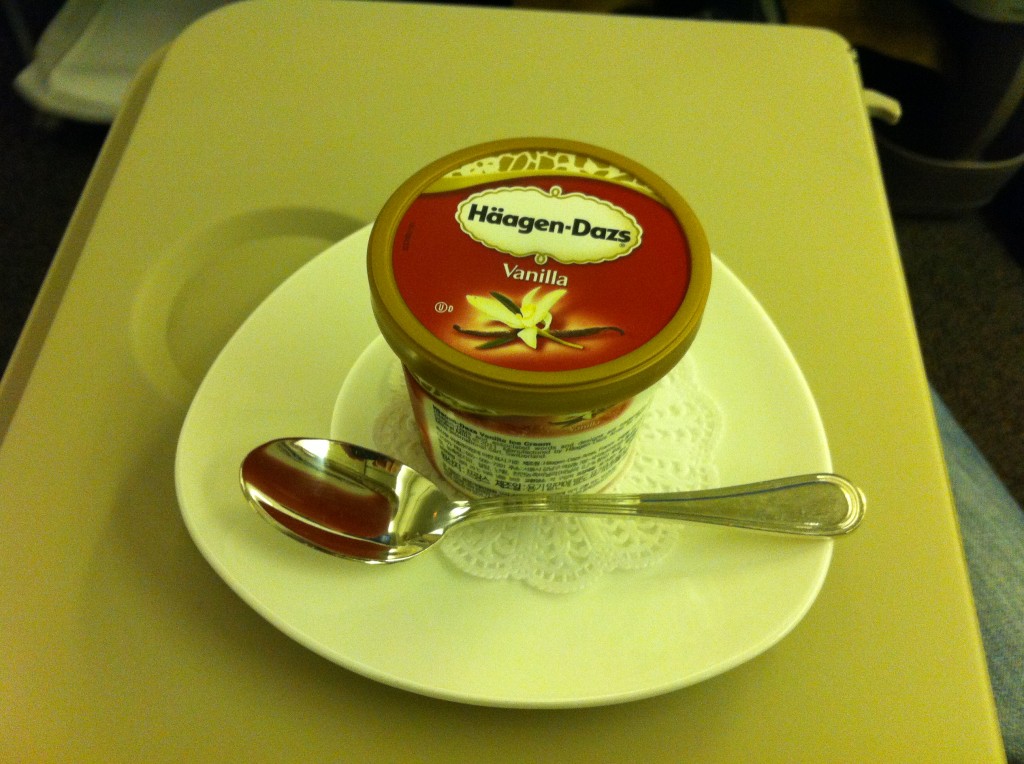 a container of vanilla ice cream on a plate with a spoon