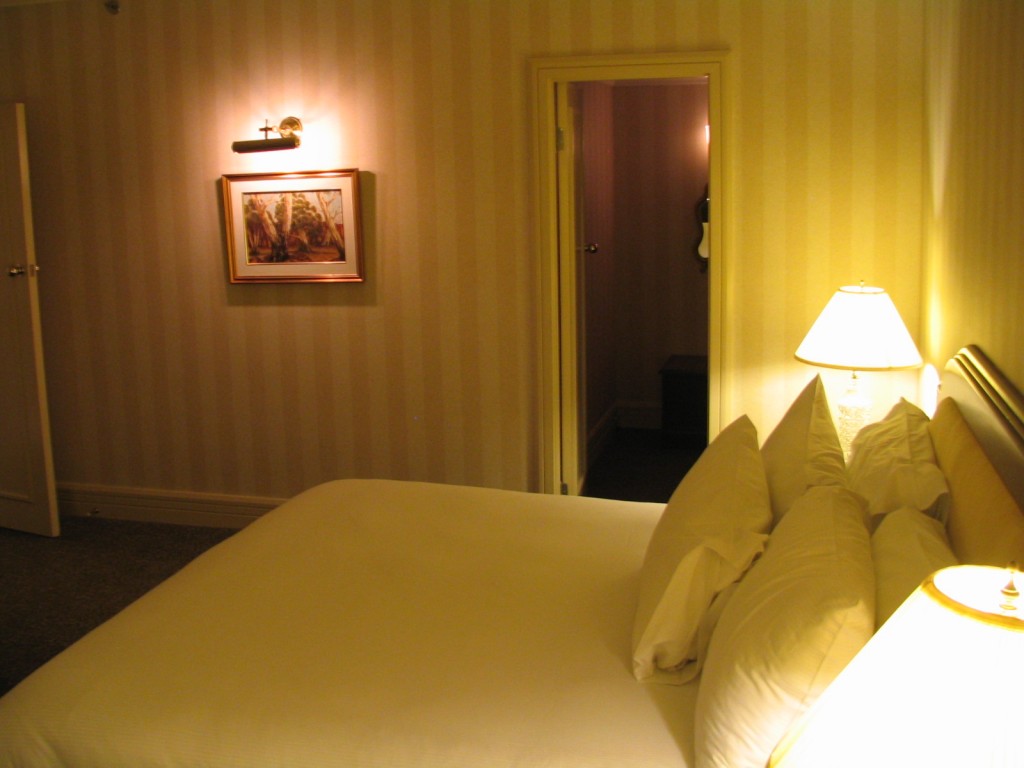 a bed with white pillows and a lamp on the wall