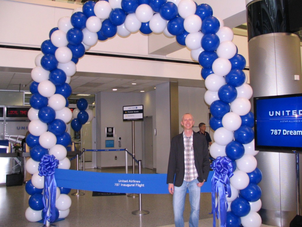 a man standing in front of a blue and white balloon arch