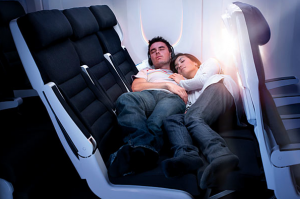 a man and woman sleeping on an airplane seat
