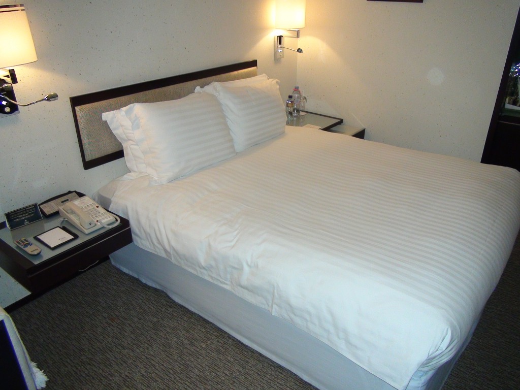 a bed with white sheets and a telephone on the side table