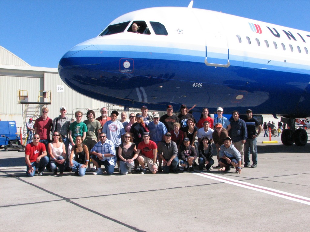 a group of people posing for a photo in front of a plane
