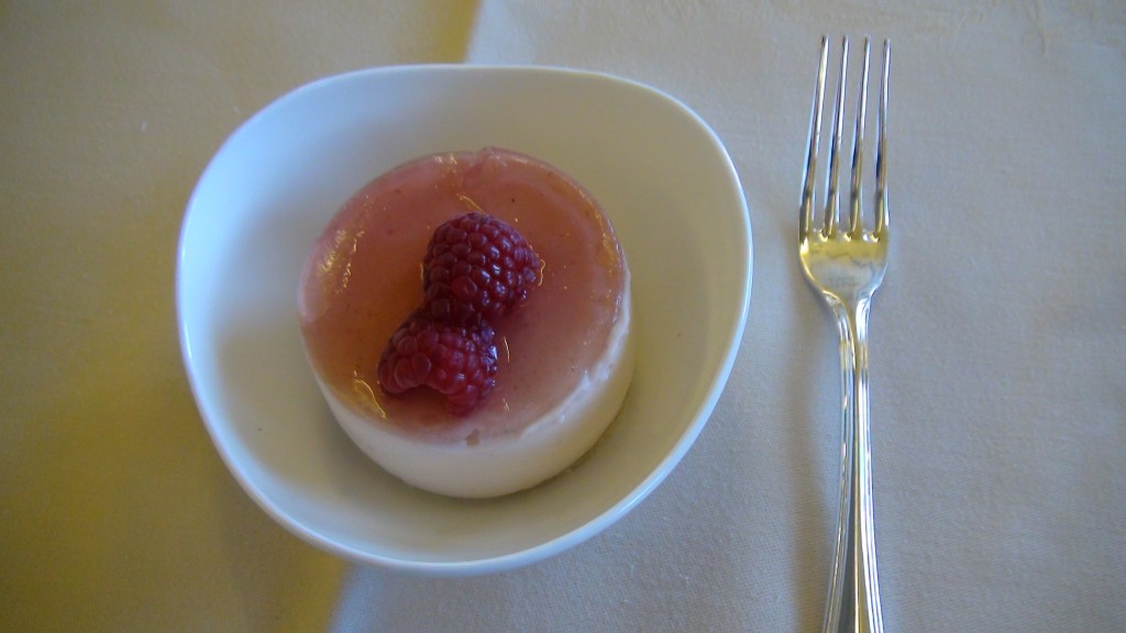 a dessert with raspberries in a bowl next to a fork