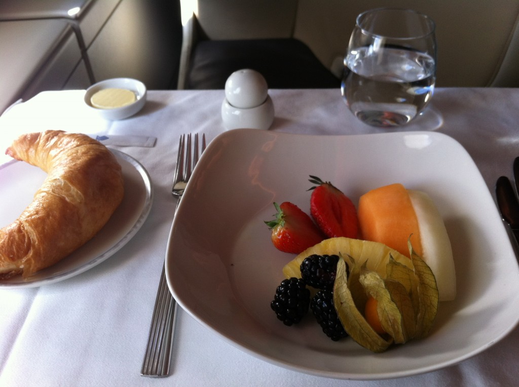 a plate of fruit and a croissant