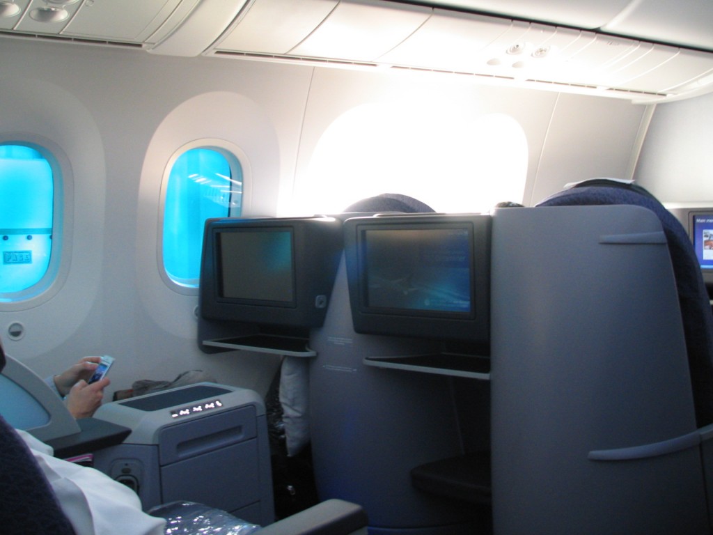 a person sitting in an airplane with a pair of monitors