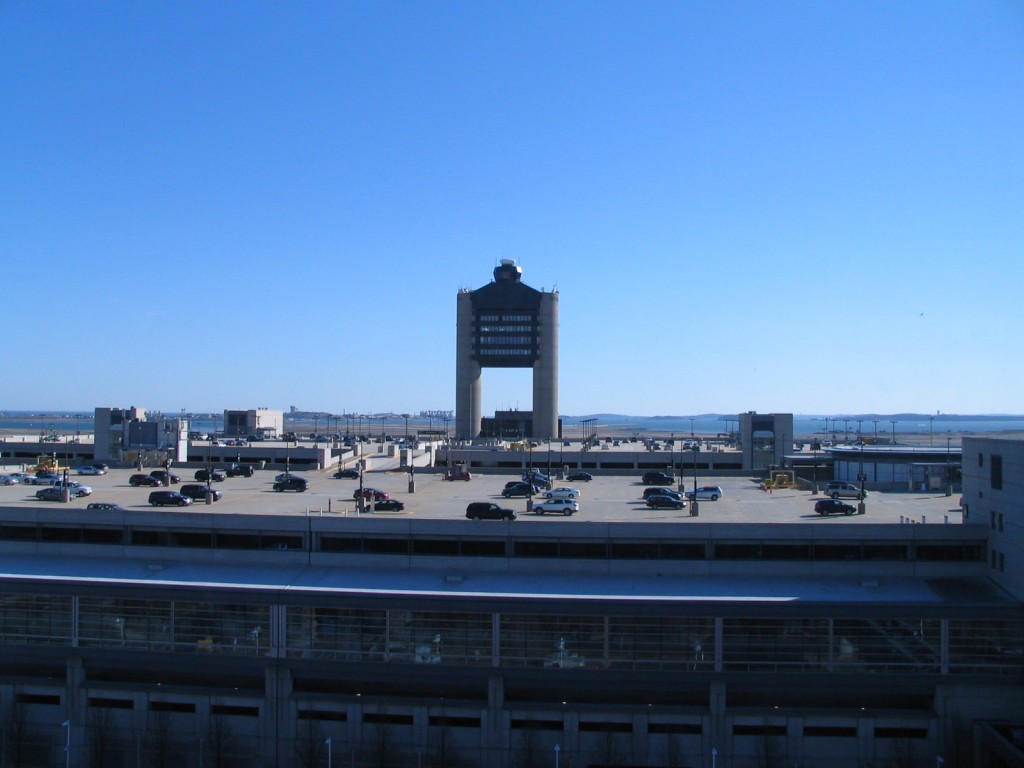 a parking lot with a large tower and cars in the background